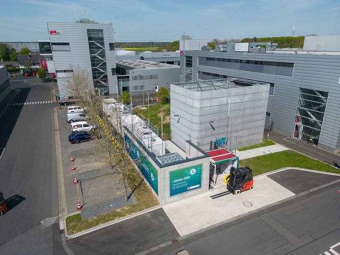Aerial view of a modern industrial complex with a forklift near a fenced container unit. Aerial view of a modern industrial complex with a forklift near a fenced container unit.