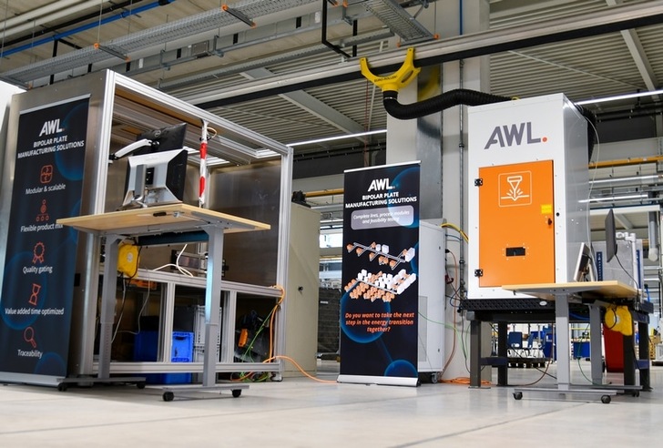 Industrial workspace with AWL manufacturing machines and informational banners in a bright factory setting. Industrial workspace with AWL manufacturing machines and informational banners in a bright factory setting.