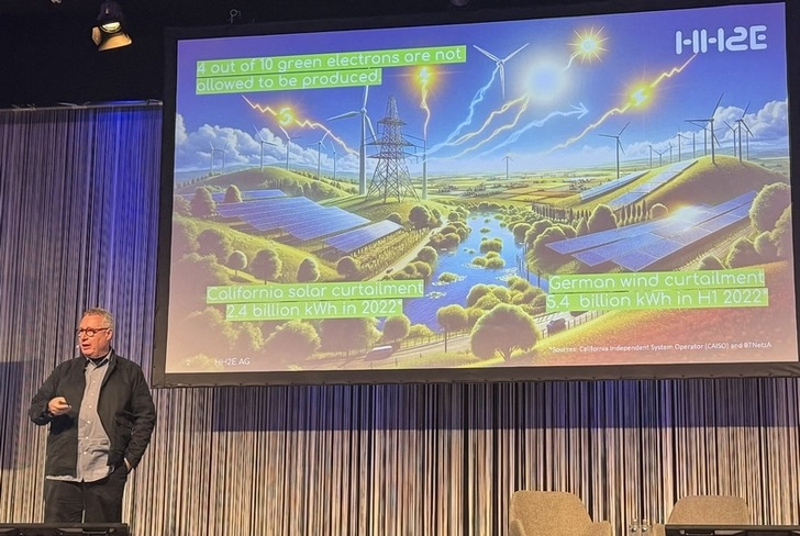 A man presents a slide on renewable energy curtailment in California and Germany at a conference. A man presents a slide on renewable energy curtailment in California and Germany at a conference.