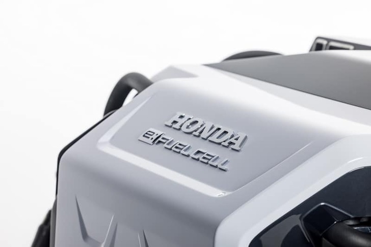 Close-up of a Honda engine cover with "Honda" and "e:Fuel Cell" embossed on it. Close-up of a Honda engine cover with "Honda" and "e:Fuel Cell" embossed on it.