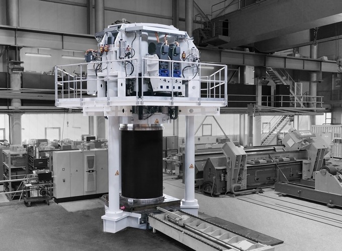 Large industrial machine with a cylindrical core in a spacious, modern factory setting. Large industrial machine with a cylindrical core in a spacious, modern factory setting.