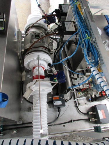 Cryogenic pipes and cables connected to machinery with control boxes and sensors visible. Cryogenic pipes and cables connected to machinery with control boxes and sensors visible.