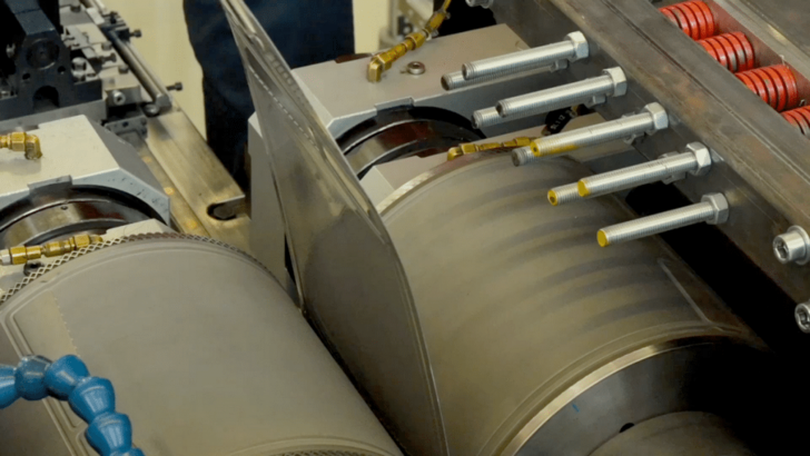 Close-up of industrial printing press rollers in operation, showing mechanical parts and metal components.