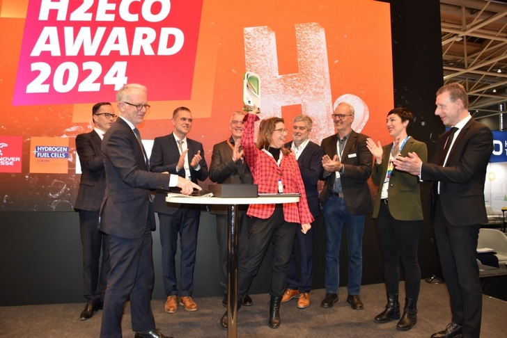 A group of people on stage applaud as a woman holds up a trophy at the H2Eco Award 2024 event. A group of people on stage applaud as a woman holds up a trophy at the H2Eco Award 2024 event.
