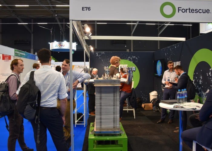 People networking at the Fortescue booth at a trade show, with a green logo visible on the display. People networking at the Fortescue booth at a trade show, with a green logo visible on the display.
