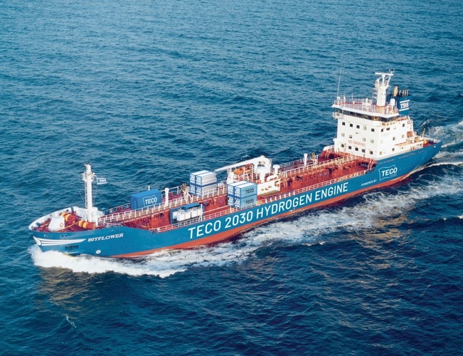 A cargo ship labeled "TECO 2030 HYDROGEN ENGINE" sails on the open sea. A cargo ship labeled "TECO 2030 HYDROGEN ENGINE" sails on the open sea.
