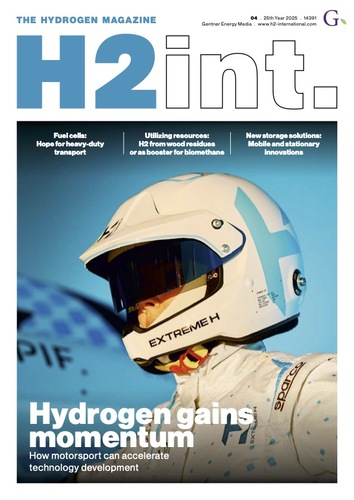 Ein Rennfahrer in weißem Helm und Anzug steht vor einem Schild mit der Aufschrift "Wasserstoff gewinnt an Fahrt".