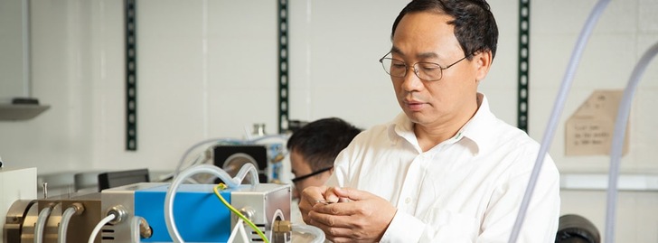 A man in a lab coat works with scientific equipment in a laboratory setting.