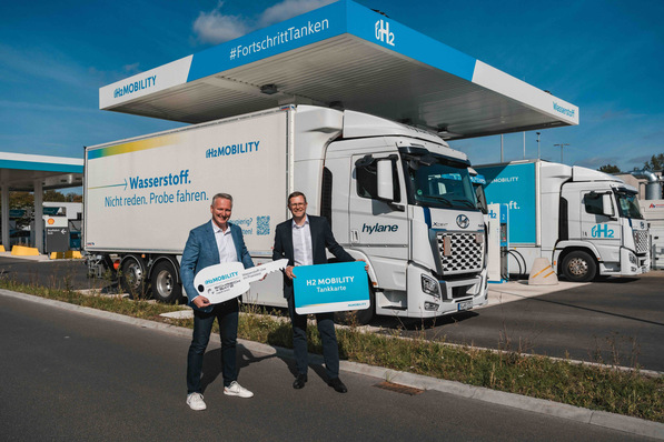 Peter Röskes, Schreck + Batz Logistik, and Martin Jüngel, H2 MOBILITY, standing in front of the hire lorry at the new hydrogen refuelling station at the Hannover Airport truck stop (from left to right).